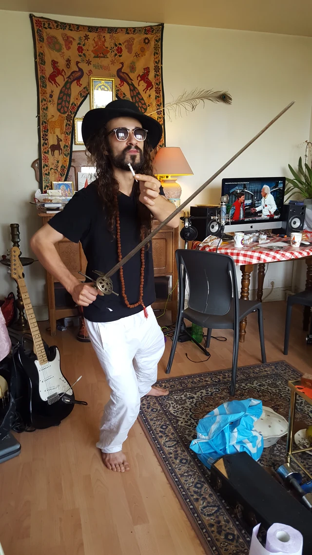 A person wearing a hat and white trousers holding a long stick in a music room.